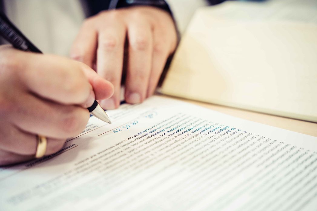 Eine Person unterschreibt ein Dokument mit einem Stift.