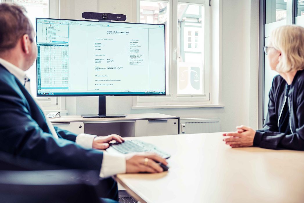 Ein Mann und eine Frau sitzen an einem Schreibtisch vor einem Computer.